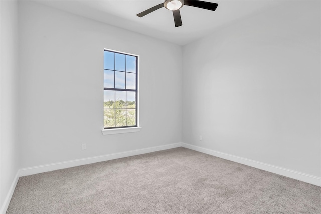 carpeted spare room featuring ceiling fan and baseboards