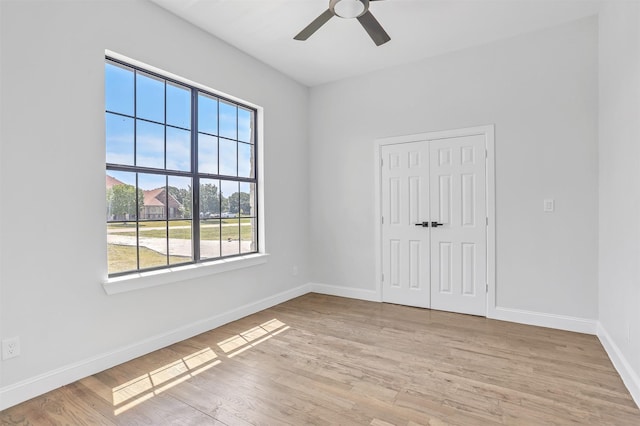 unfurnished bedroom with light wood-style floors, baseboards, a closet, and ceiling fan