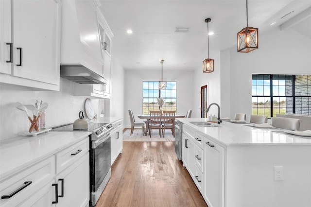 kitchen with visible vents, a sink, wall chimney range hood, appliances with stainless steel finishes, and light wood finished floors