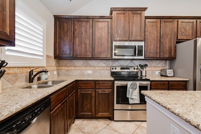 kitchen featuring a sink, backsplash, stainless steel appliances, light tile patterned flooring, and light stone countertops