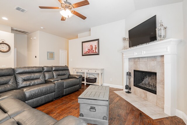 living area featuring a tiled fireplace, visible vents, and wood finished floors