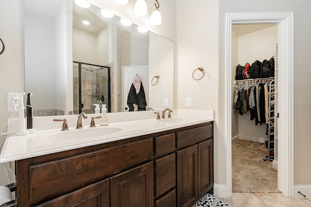 full bathroom with a sink, double vanity, a stall shower, and a spacious closet