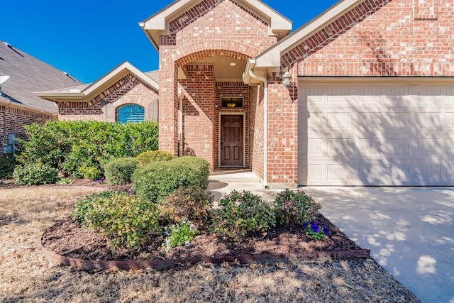 doorway to property featuring concrete driveway, a garage, and brick siding