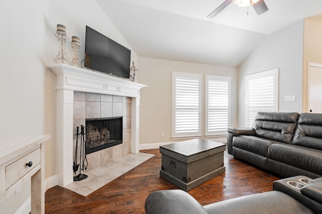 living area featuring wood finished floors, a fireplace, baseboards, ceiling fan, and vaulted ceiling