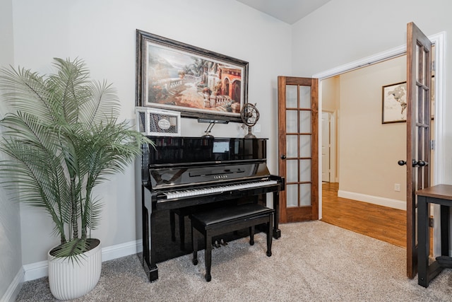 living area with carpet flooring, french doors, baseboards, and wood finished floors