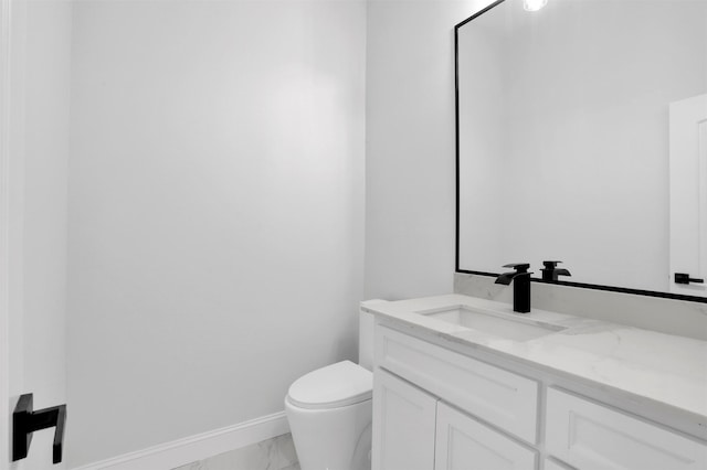 half bathroom featuring vanity, toilet, baseboards, and marble finish floor