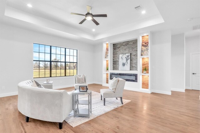 sitting room with visible vents, light wood-style flooring, and a raised ceiling