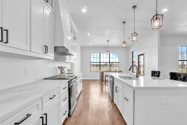 kitchen with a sink, stainless steel appliances, white cabinets, light wood finished floors, and custom exhaust hood