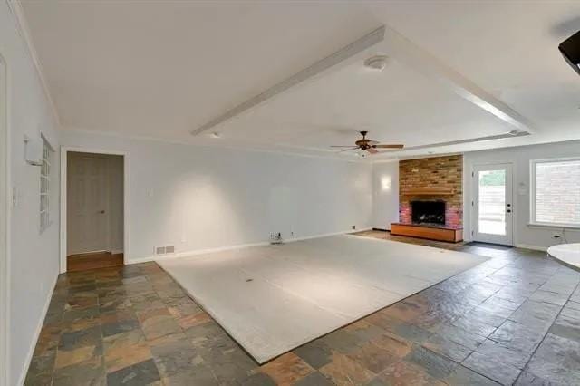 unfurnished living room with visible vents, baseboards, a brick fireplace, and ceiling fan