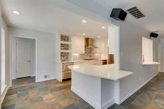 kitchen with tasteful backsplash, visible vents, wall chimney range hood, light countertops, and recessed lighting