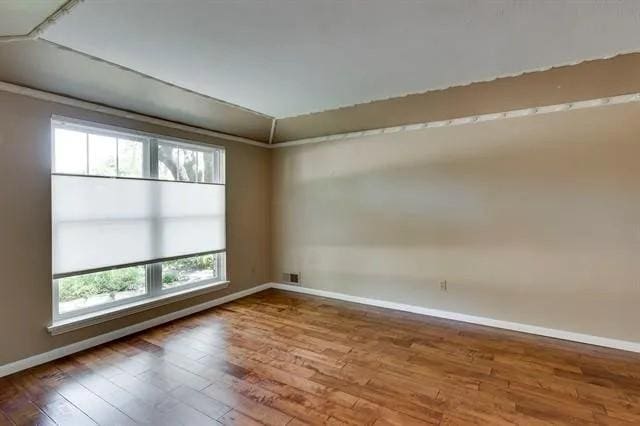 empty room featuring visible vents, baseboards, and wood finished floors