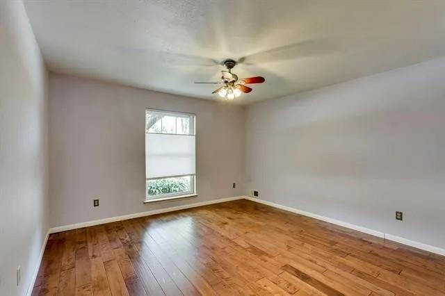 unfurnished room with ceiling fan, baseboards, and wood-type flooring