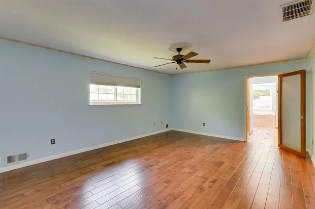 empty room with hardwood / wood-style flooring, visible vents, and a wealth of natural light