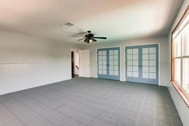 empty room with french doors, visible vents, and a ceiling fan