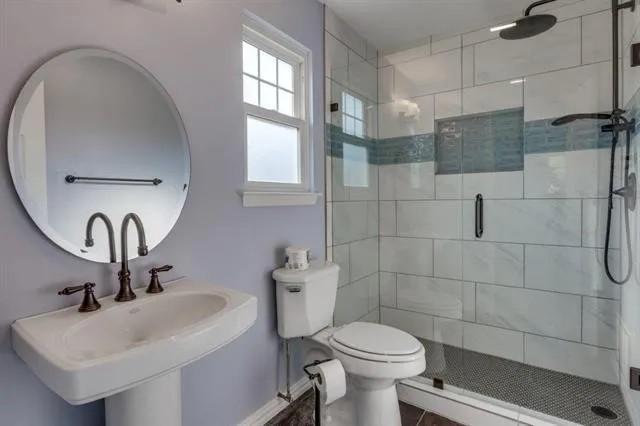 bathroom featuring a sink, toilet, and a stall shower