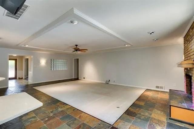 unfurnished living room with visible vents, a ceiling fan, a fireplace, and stone finish floor