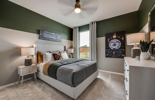 bedroom featuring baseboards, light colored carpet, and a ceiling fan