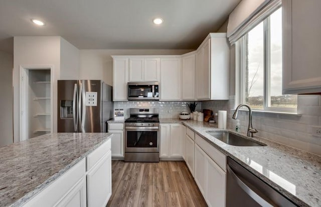 kitchen with light wood-style flooring, white cabinets, appliances with stainless steel finishes, and a sink