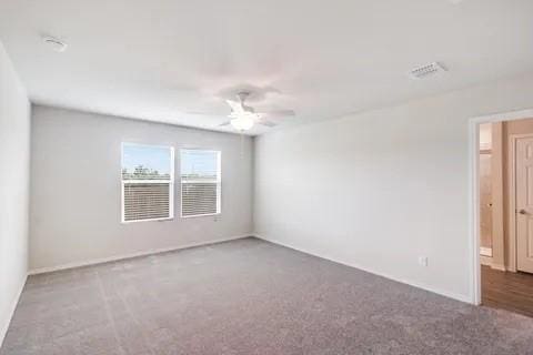 spare room with visible vents, carpet floors, and a ceiling fan