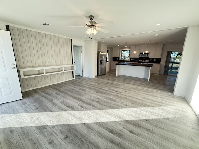 kitchen with visible vents, light wood-style floors, appliances with stainless steel finishes, dark countertops, and open floor plan