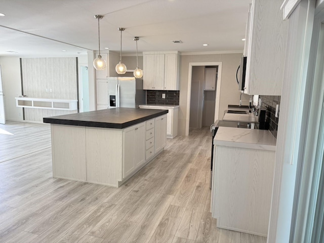 kitchen featuring white cabinets, light wood-style flooring, appliances with stainless steel finishes, and a fireplace