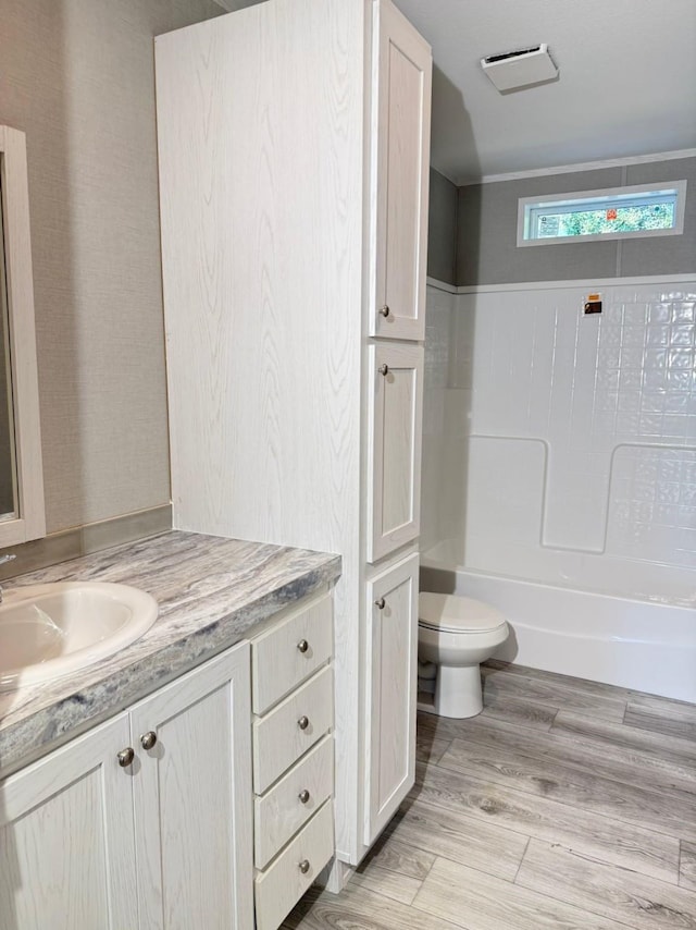 bathroom featuring visible vents, toilet, wood finished floors, shower / bathing tub combination, and vanity