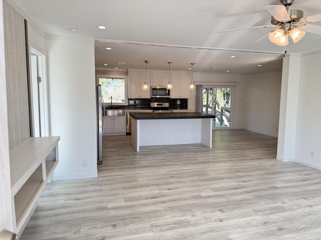 kitchen featuring a sink, backsplash, dark countertops, open floor plan, and stainless steel appliances