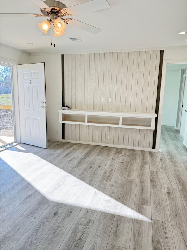 interior space with a ceiling fan, access to exterior, wood finished floors, and visible vents