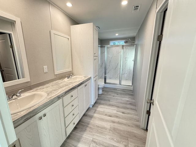 bathroom featuring a marble finish shower, visible vents, wood finished floors, and a sink