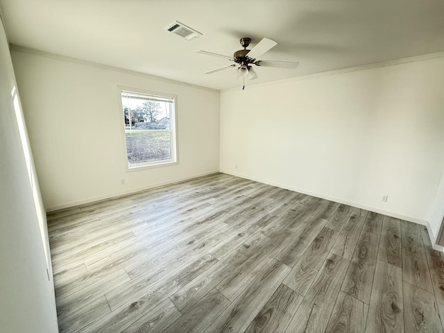 empty room with visible vents, wood finished floors, crown molding, baseboards, and ceiling fan