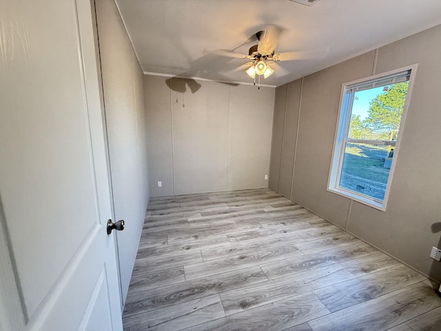 unfurnished room featuring a decorative wall, visible vents, light wood finished floors, and ceiling fan