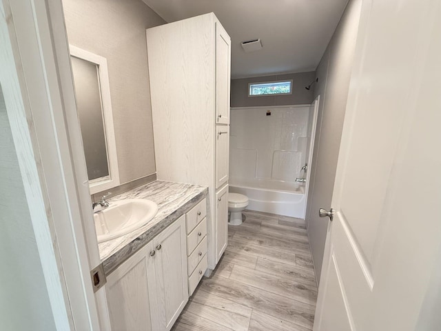 bathroom with shower / bathtub combination, toilet, vanity, and wood finished floors