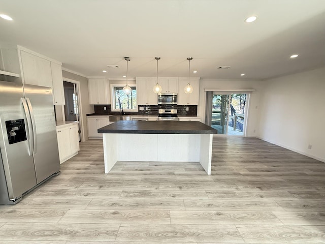 kitchen with light wood-style flooring, tasteful backsplash, a center island, appliances with stainless steel finishes, and white cabinets