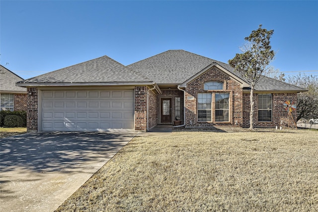 single story home featuring concrete driveway, an attached garage, brick siding, and roof with shingles