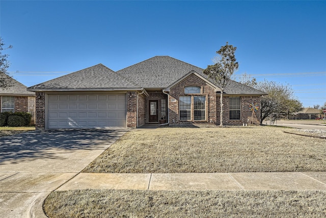 view of front of house featuring a front yard, roof with shingles, an attached garage, concrete driveway, and brick siding