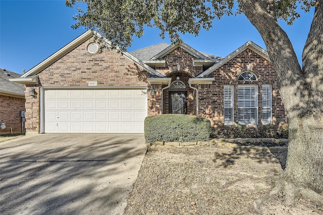 view of front of house featuring concrete driveway, an attached garage, and brick siding