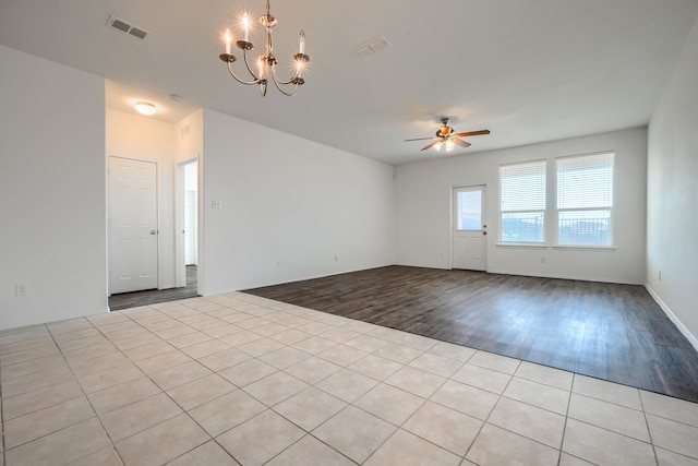 empty room featuring visible vents, wood finished floors, and ceiling fan with notable chandelier