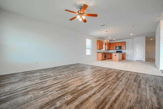 unfurnished living room with recessed lighting, visible vents, ceiling fan with notable chandelier, and light wood finished floors