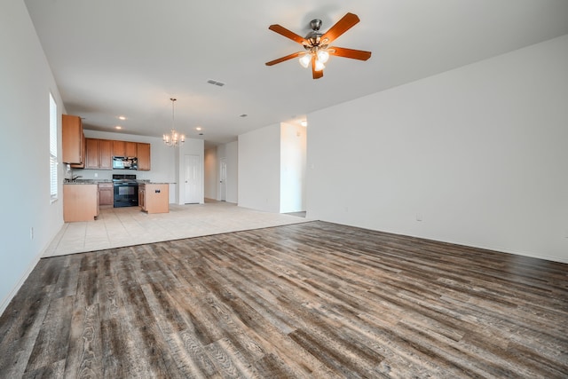 unfurnished living room featuring recessed lighting, visible vents, ceiling fan with notable chandelier, and light wood-type flooring