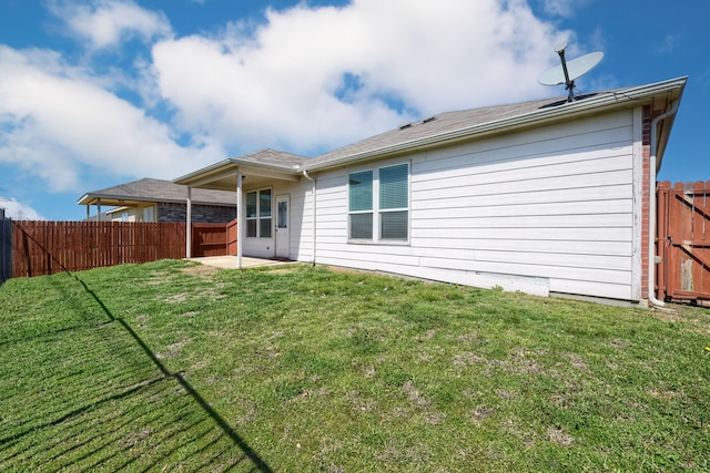 back of house featuring a yard, a patio, and a fenced backyard