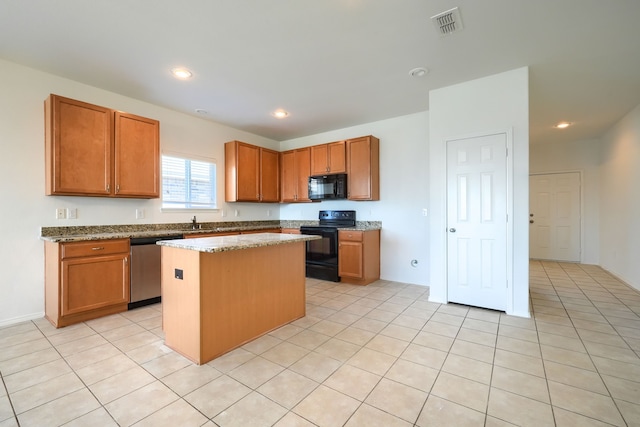 kitchen featuring visible vents, black appliances, a center island, recessed lighting, and light stone countertops