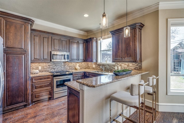 kitchen featuring a breakfast bar, tasteful backsplash, appliances with stainless steel finishes, and pendant lighting