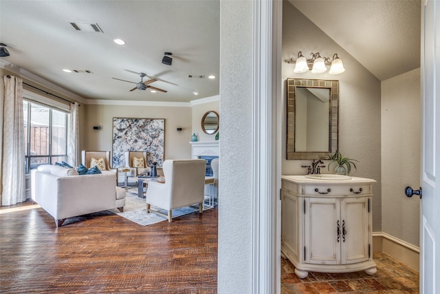 living room with visible vents, a fireplace, ornamental molding, dark wood-type flooring, and a textured wall