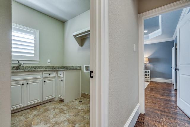 laundry area featuring a sink, baseboards, crown molding, and a textured wall