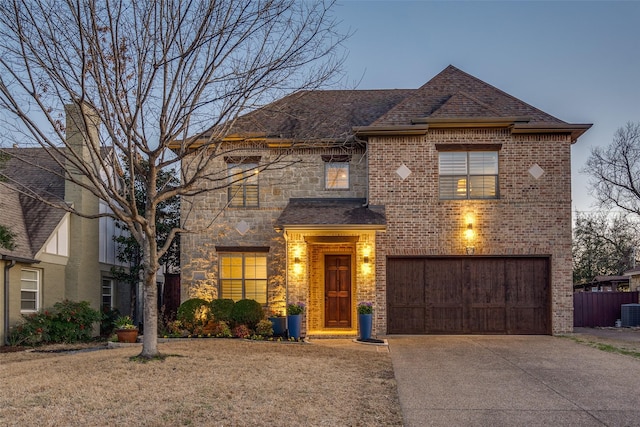 view of front facade with brick siding, a shingled roof, a garage, stone siding, and driveway