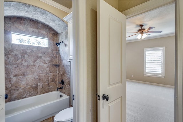 bathroom with a wealth of natural light, washtub / shower combination, toilet, and crown molding