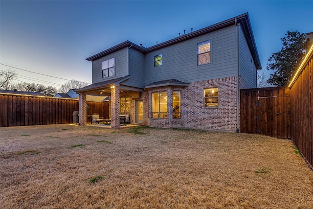 back of property with brick siding, a lawn, and a fenced backyard