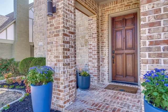 doorway to property with brick siding and roof with shingles