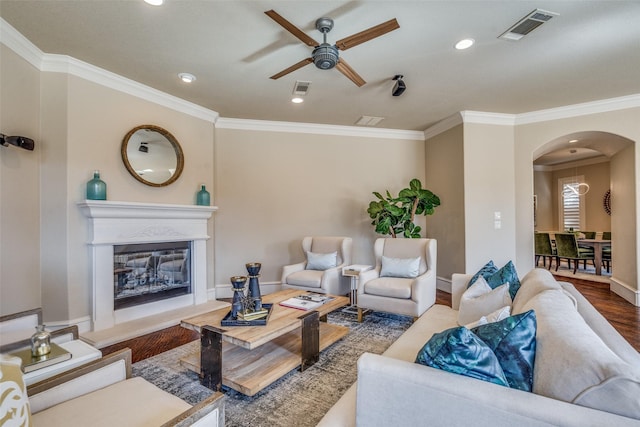 living area featuring a glass covered fireplace, wood finished floors, arched walkways, and visible vents