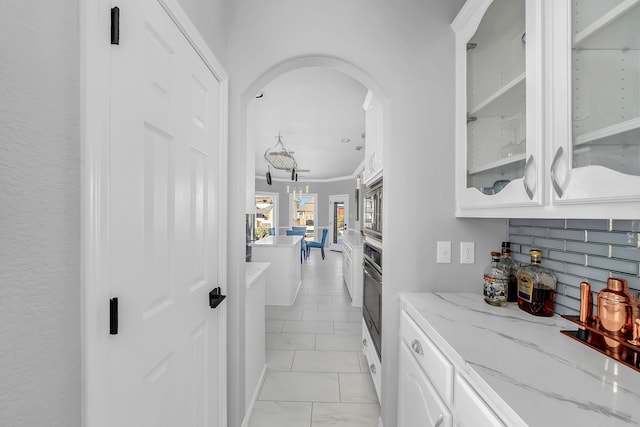 kitchen with light stone counters, tasteful backsplash, white cabinetry, stainless steel appliances, and glass insert cabinets